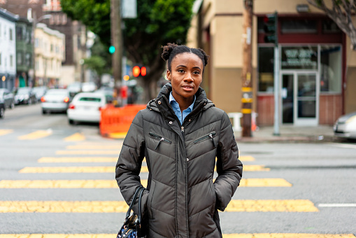 A young woman crossing the street in the Mission District of San Francisco, USA.