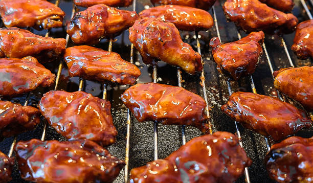 ailes de poulet bbq marinées sur une grille de cuisson, gros plan. - barbecue grill broiling barbecue vegetable photos et images de collection
