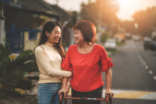 una femmina asiatica cinese che cammina con il suo aiuto a piedi recuperando e aiutato da sua figlia - malaysian person family asian ethnicity mother foto e immagini stock