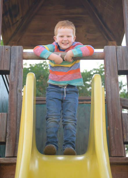 istock 5 years old redheaded happy boy smiling on a slide 1157387743