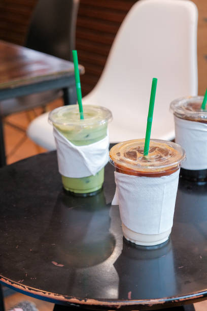 ice coffee and matcha green tea cold drink in takeaway or to go cup on wooden table at cafe