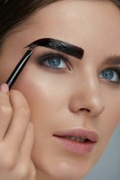 istock Eyebrow coloring. Woman applying brow tint with makeup brush 1157389720