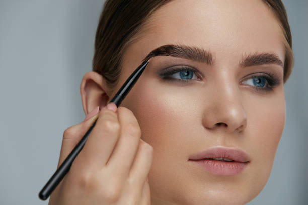 istock Eyebrow coloring. Woman applying brow tint with makeup brush 1157389924