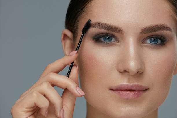 istock Eyebrow makeup. Woman brushing brows with gel brush closeup 1157391504