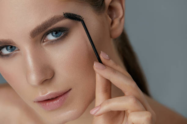 Eyebrow makeup. Woman brushing brows with gel brush closeup Eyebrow makeup. Woman brushing brows with brush closeup. Girl model with beautiful eyes shaping eyebrows with brow gel lash and brow comb stock pictures, royalty-free photos & images