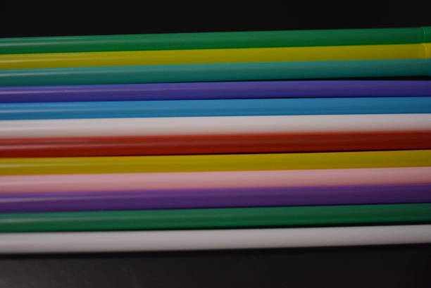 istock Multi-colored plastic stickers, tubes laid out in a graphic and rainbow format.  Tubules were used to decorate glasses and cocktails for parties and events.  Interesting light background and image. 1157392247