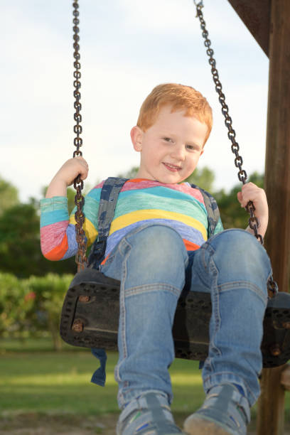 istock 5 years old redheaded happy boy with his backpack swinging and smiling 1157396228
