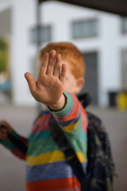 istock 5 years old redheaded boy with his hand raised up in a stop gesture 1157398386