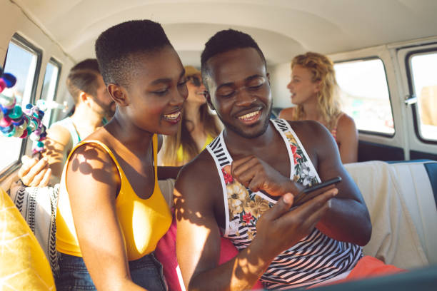 istock Friends discussing over mobile phone in camper van at beach 1157401561