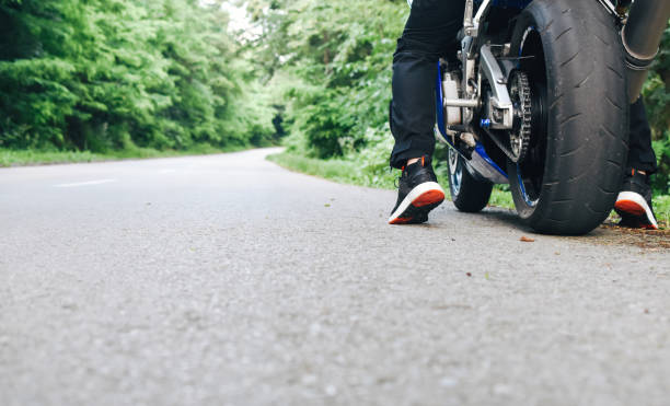 istock Man starting riding on motorcycle from roadside 1157414123