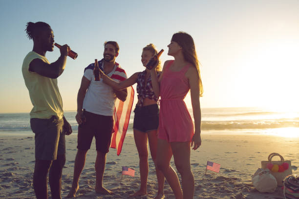 istock Group of friends drinking beer at beach during sunset 1157414992