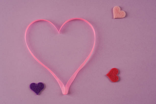 istock pink ribbon heart on purple background 1157424326