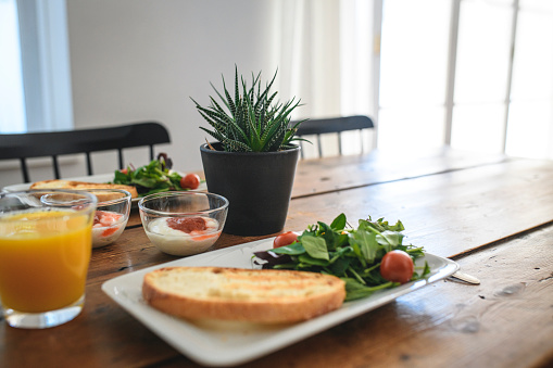 The day begins with a delicious breakfast of toasted bread, salad, and yogurt on a wooden dining table.