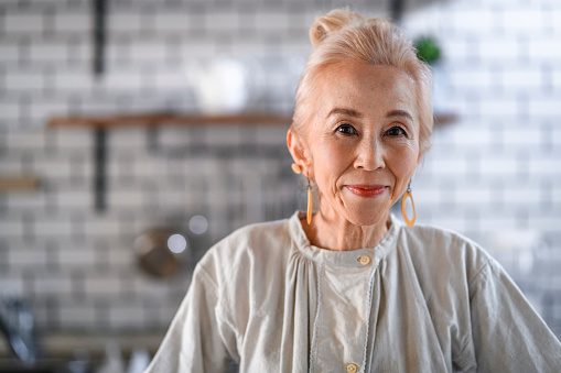 Portrait of a beautiful poised senior Japanese woman standing in her kitchen at the start of a new day.