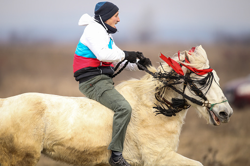 Pietrosani, Romania - January 6, 2019: Man is bareback riding an adorned horse before an Epiphany celebration horse race.