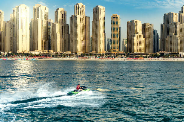 homem que bashing as ondas no mar com skyline do dubay no fundo - jumeirah beach hotel - fotografias e filmes do acervo