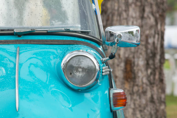 Lights in front of a vintage car with a unique sphere.\