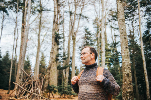 istock Handsome middle age man hiking in forest, wearing pullover, backpack and glasses 1157428990