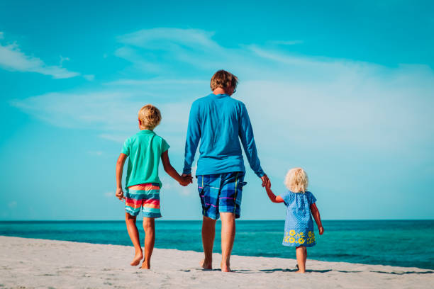 istock father and two kids walking on beach 1157431926