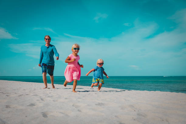 istock father with little daughters play, run at beach 1157431951