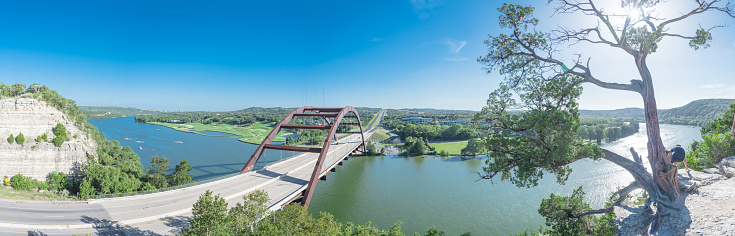 Panorama elevated view of Pennybacker Bridge or 360 Bridge with limestone cliff. A landmark in Austin, Texas, USA. Top of Town Lake, Colorado River and Hill Country green landscape