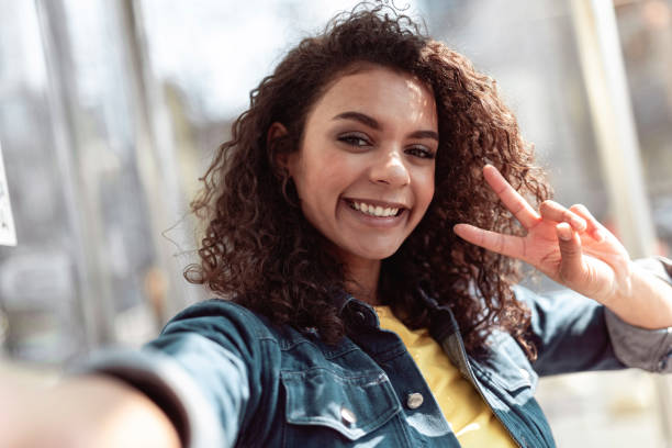 istock Joyful curly girl is gesturing peace sign 1157432671
