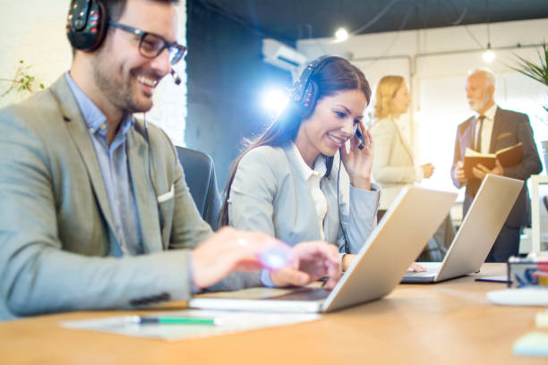 istock Smiling customer support workers talking with clients in call center. Focus on beautiful young woman with headset. 1157434035