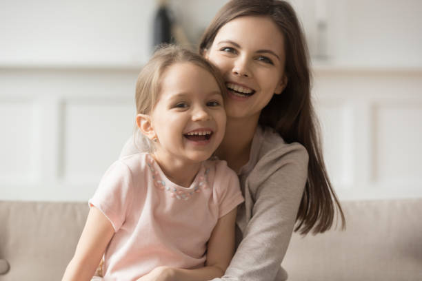 istock Happy kid sitting on mothers lap laughing looking at camera 1157439236