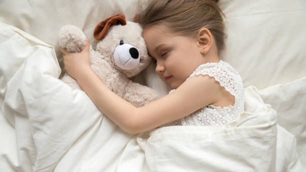 istock Slumber kid embrace stuffed toy sleeping in bed top view 1157439261