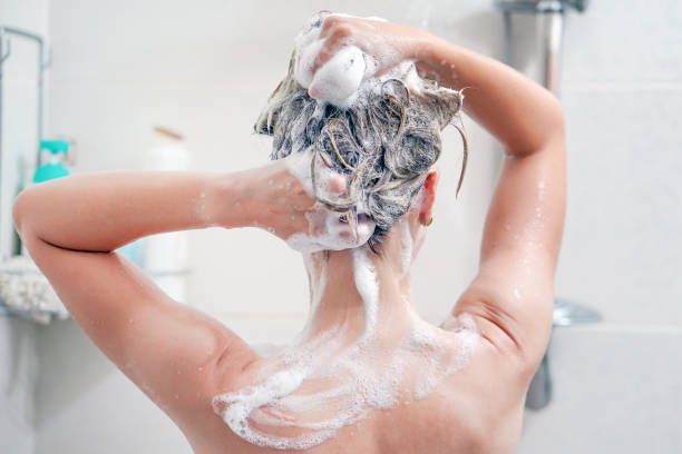 achteraanzicht van de jonge vrouw die haar haar wast - douchen stockfoto's en -beelden