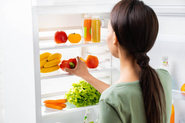 istock Young lady taking sweet pepper from refrigerator 1157441083
