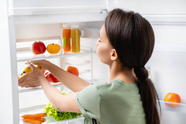 istock Young pretty lady taking bananas from refrigerator 1157441088