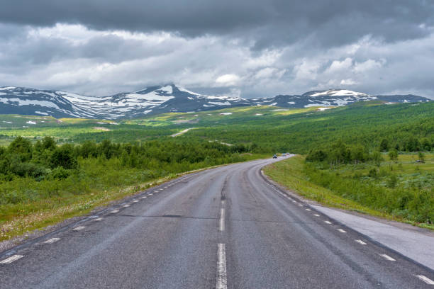 national road 95 in sweden in approach of norwegian frontier merkenisvuopmekietje. tundra forest valleys and scandinavian mountains partially hided with clouds are at background. - norrland imagens e fotografias de stock