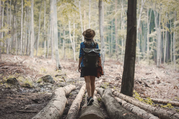 istock Style girl in hat with backpack in a summer time Mixed coniferous forest 1157443876