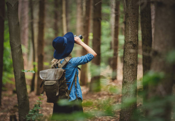 Young woman with binocular and backpack in a forest