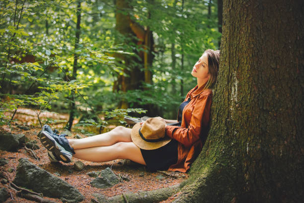 Style girl with backpack sitting in a stone in a summer time mixed coniferous forest