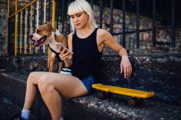 Young Woman Text Messaging Young woman text messaging outdoors and her dog sitting beside her. hipster dog stock pictures, royalty-free photos & images