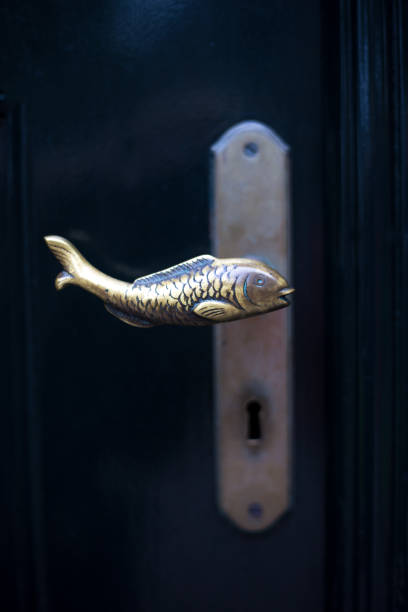 Friesland, Netherlands: Bronze fish doorknob on dark door with plenty of copy space.