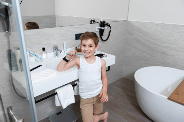 le petit garçon retient une brosse à dents dans la salle de bains - brushing teeth photos et images de collection
