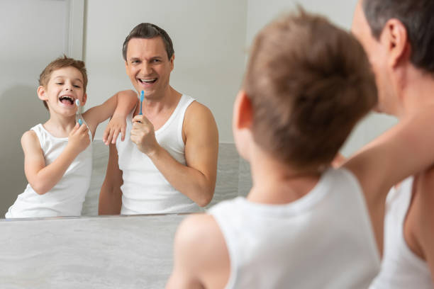 istock Smiling dad and son brushing their teeth together 1157450972