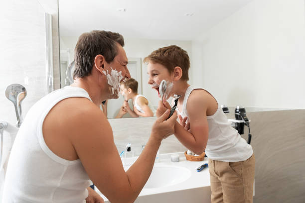 padre e hijo felices están de pie cerca de miror y se afeitan - shaving equipment wash bowl bathroom razor fotografías e imágenes de stock