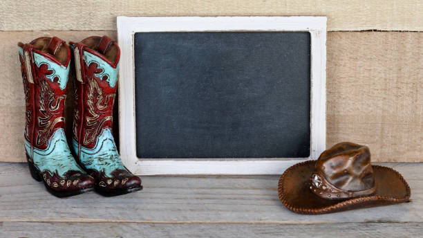 cowboy boots and hat next to a chalkboard on a wood background