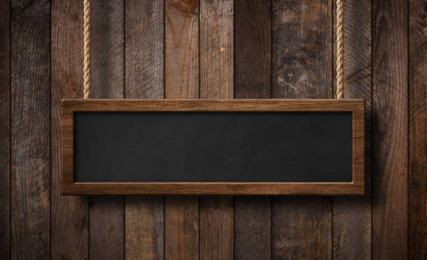istock Oblong blackboard hanging on ropes with wood planks background 1157453990
