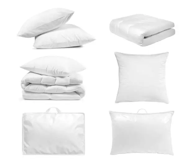 White bedroom textile items set isolated. Pillows and duvet- laying, folded, stacked and packed against the white background.