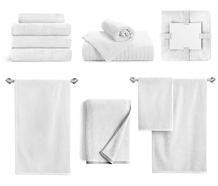 White bath textile items set isolated. Cotton terry towels- hanging, folded, stacked and packed against white background.