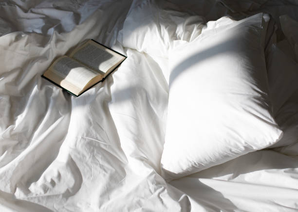 istock Creative photo composition with book and white bed under the sun light from window 1157464210
