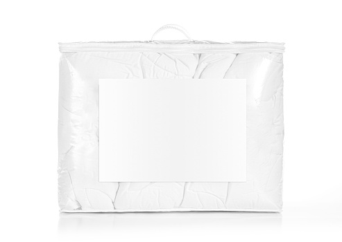 White duvet or bedspread in the retail bag isolated. Duvet packed in to the PVC bag with empty label, front view against white background. Photo ready to mock up.