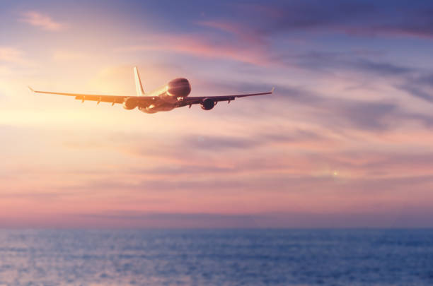 istock Airplane flying over blur tropical beach and sunset sky abstract background. Copy space of business summer vacation and travel adventure concept. Vintage tone filter effect color style. 1157475131