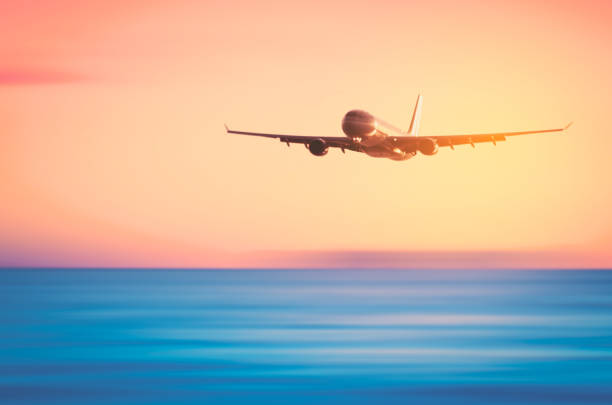 istock Airplane flying over blur tropical beach and sunset sky abstract background. Copy space of business summer vacation and travel adventure concept. Vintage tone filter effect color style. 1157475163