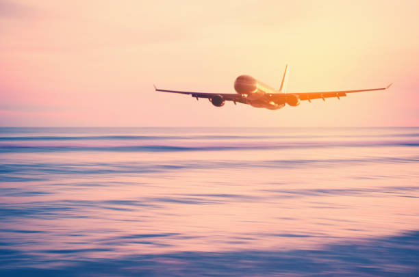 istock Airplane flying over blur tropical beach and sunset sky abstract background. Copy space of business summer vacation and travel adventure concept. Vintage tone filter effect color style. 1157475200